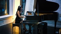 a woman in a black dress sitting at a piano